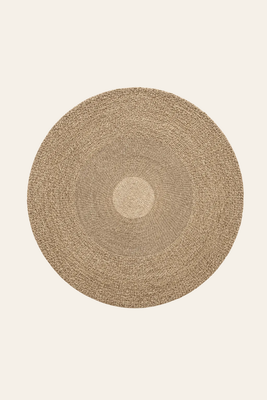 Groot rond vloerkleed van natuurlijk zeegras op een licht beige achtergrond