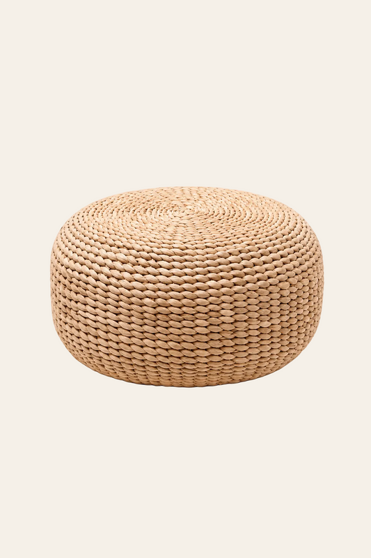 Ronde handgeweven poef in naturel waterhyacint in een lichtbeige product foto achtergrond
