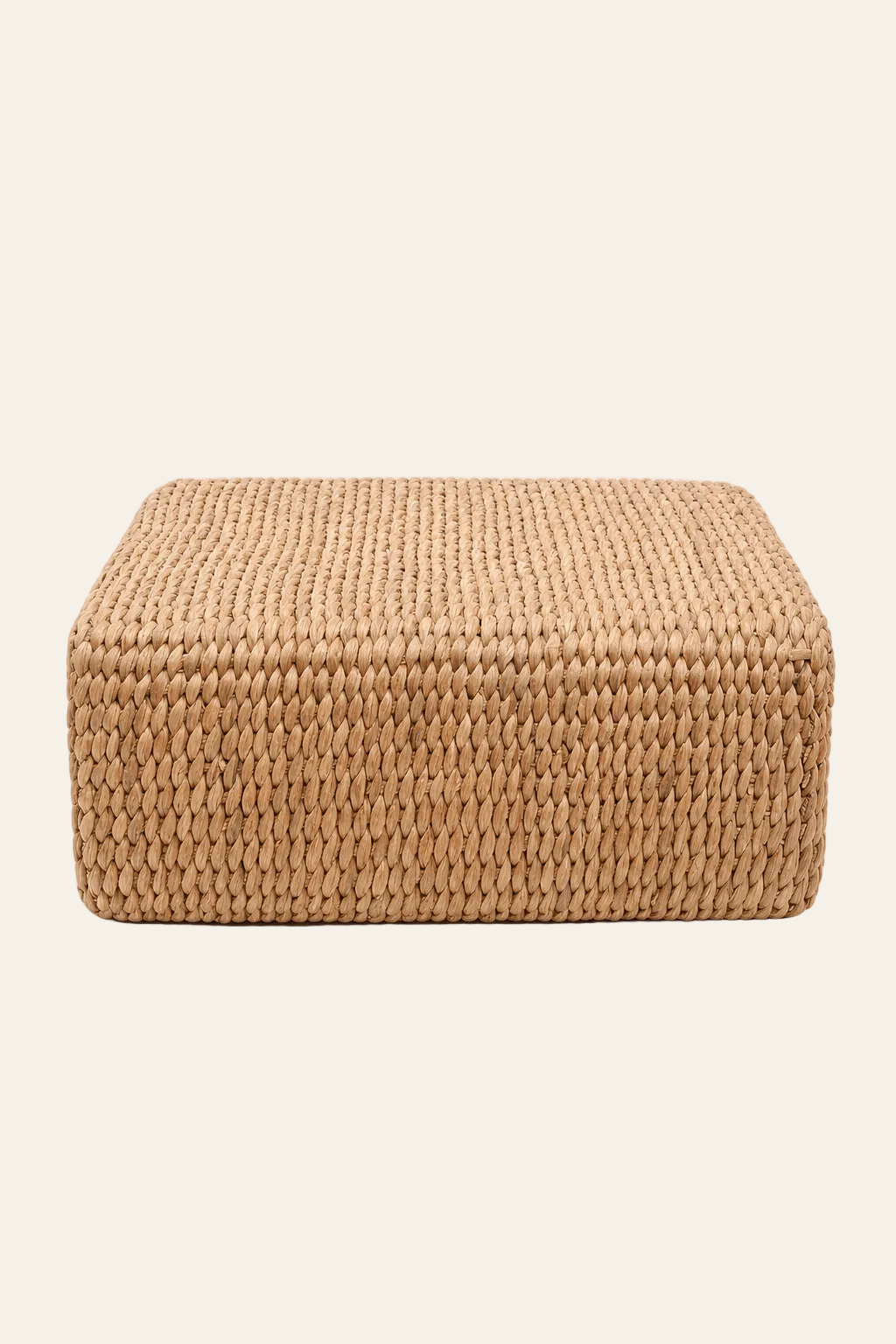 Handgeweven vierkante poef in naturel waterhyacint in een lichtbeige achtergrond productfoto
