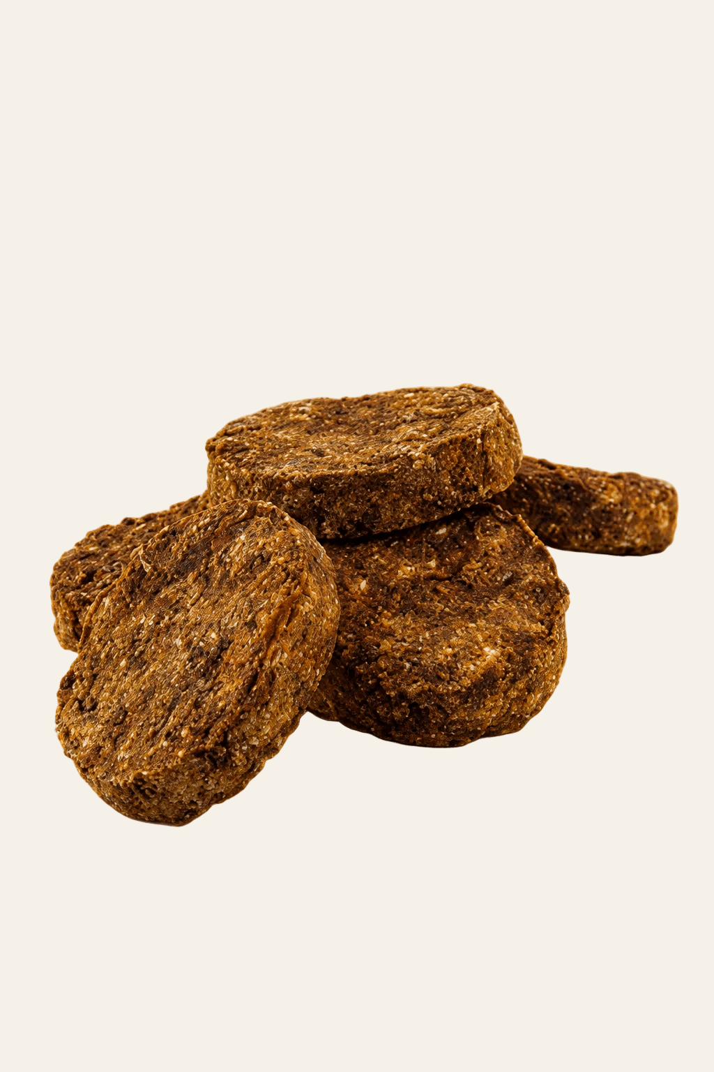 Dogstar Pensburgers 5 kg, bruine ronde hondensnacks met runderpens en stevige structuur, gestapeld op een beige achtergrond.