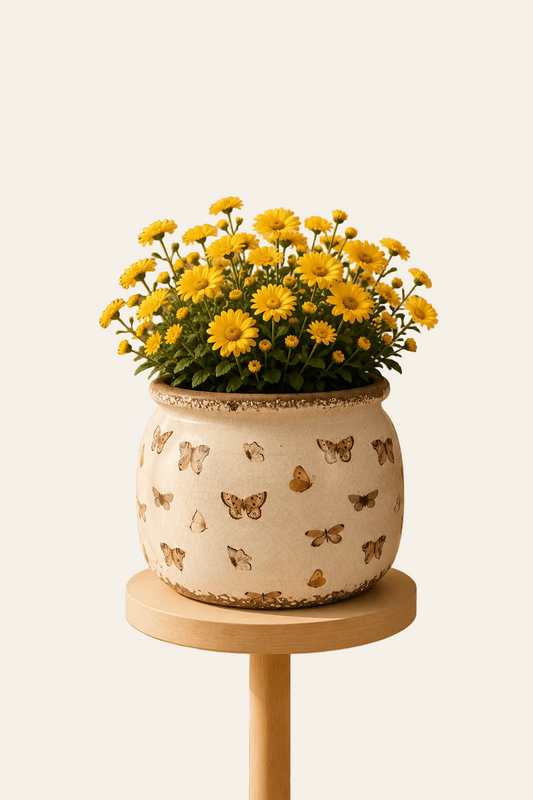 Keramische bloempot met vlindermotief met een bloemboeket.