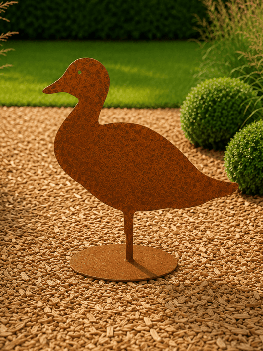 Roestige decoratieve eend op vloerplaat pronkend tussen de bloemen en planten in een grote tuin met dieptezicht
