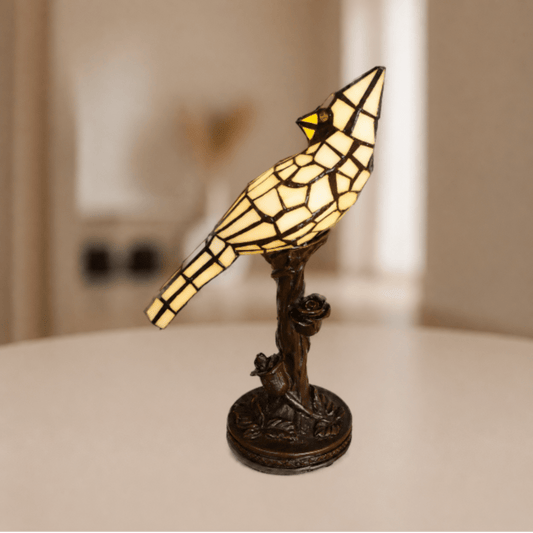 Brandende Tiffany vogellamp met beigekleurig glas-in-lood en warme gloed boven boomtakvoet