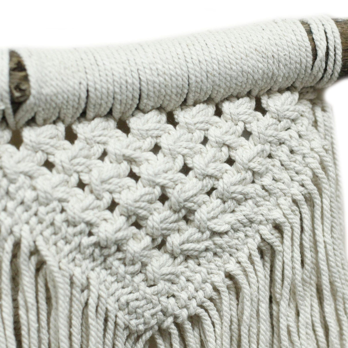 Detailfoto van de print hoe de macrame geknoopt is en hoe deze rond de houten stok hangt.