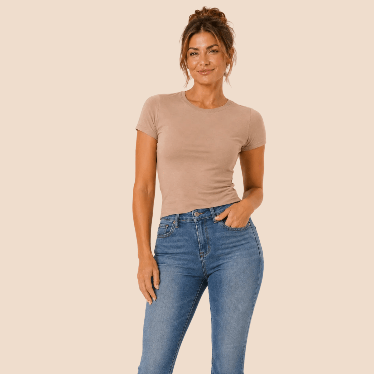 LMB Boutique model in een lichtbeige T-shirt en gewassen jeansbroek op een lichte achtergrond