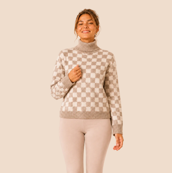 Model van LMF Fashion die een lichtbeige legging en gebreide dambordmotief trui toont op een lichtbeige achtergrond
