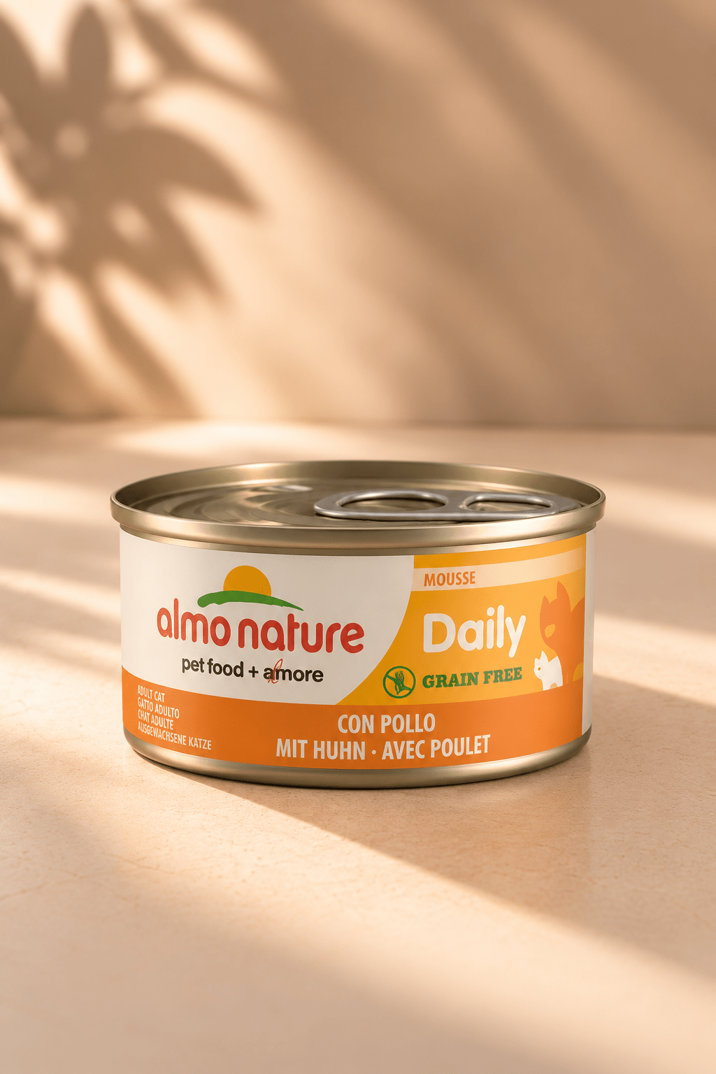 Almo Nature Daily Menu graanvrije kattenmousse met kip in oranje-wit blikje van 85 gram, op beige achtergrond met bladschaduw.