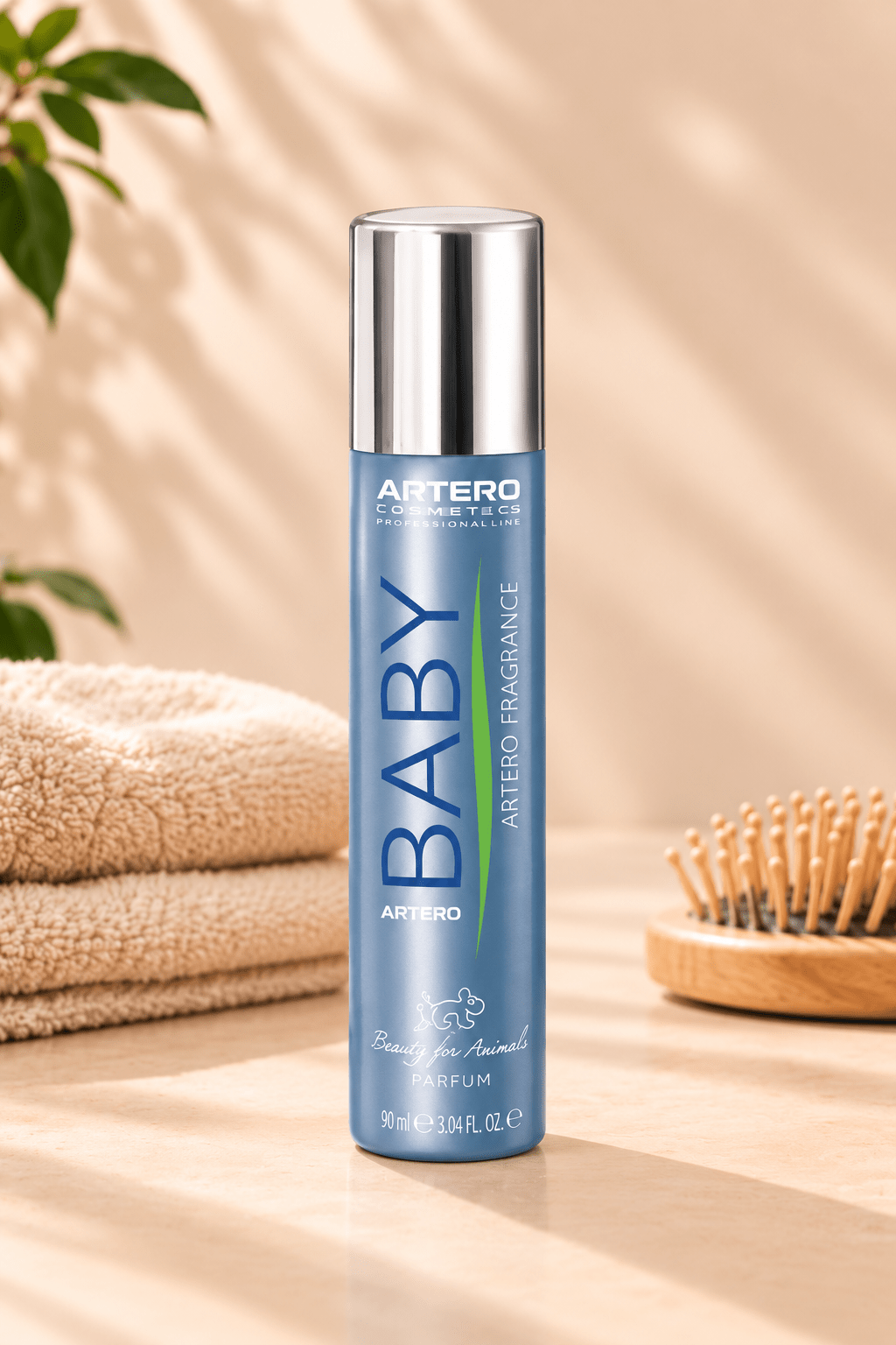 Blauwe Artero Baby parfumspray 90 ml met zilveren dop op een lichtbeige ondergrond naast zachte handdoeken en houten hondenborstel.
