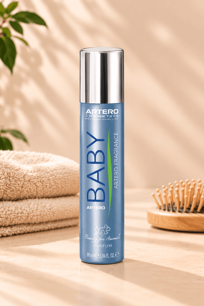 Blauwe Artero Baby parfumspray 90 ml met zilveren dop op een lichtbeige ondergrond naast zachte handdoeken en houten hondenborstel.