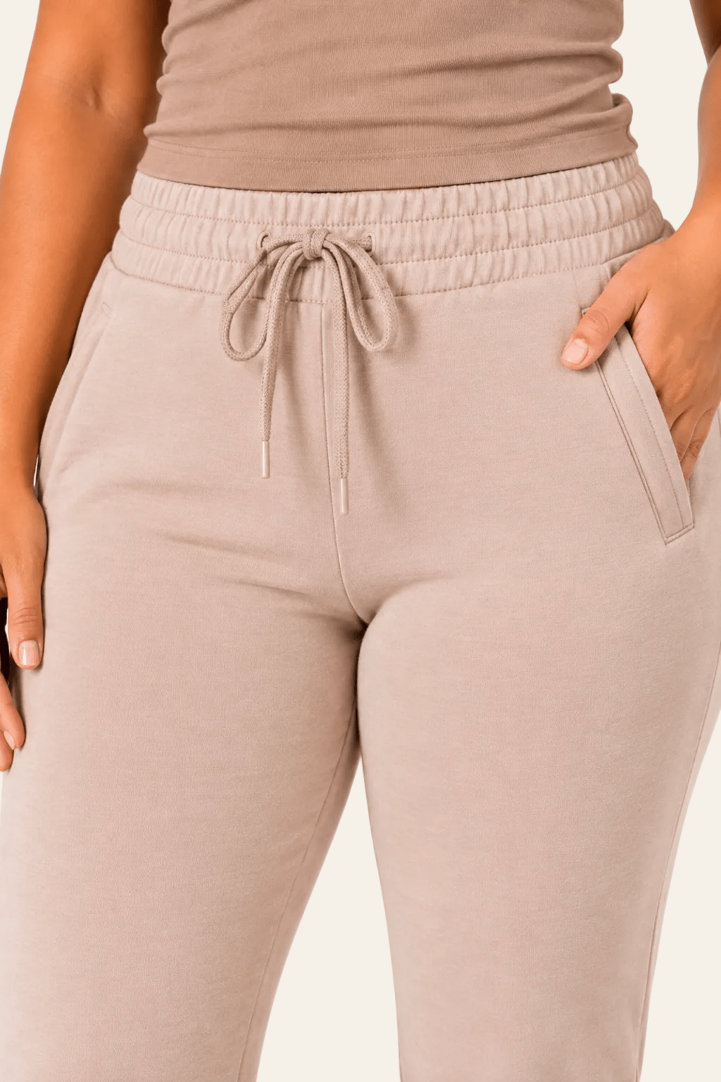 Detail van hoge taille, zijzak en printdetail van beige damesjoggingbroek.