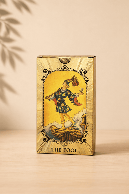 Blauw-gouden tarotkaartenset met alziend oog en boekje op een beige gebladerde achtergrond