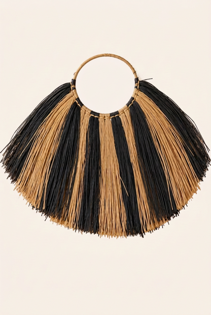 Handgemaakte zeegras wanddecoratie met zebraprint in zwart en naturel, ronde ophangring en brede waaiervorm op een neutrale lichtbeige achtergrond.