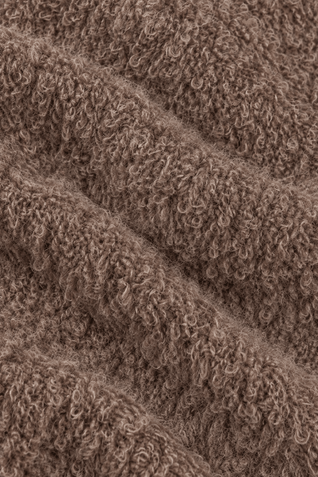 Detail van de bouclé stofstructuur van damestrui met decoratieve stiksels.