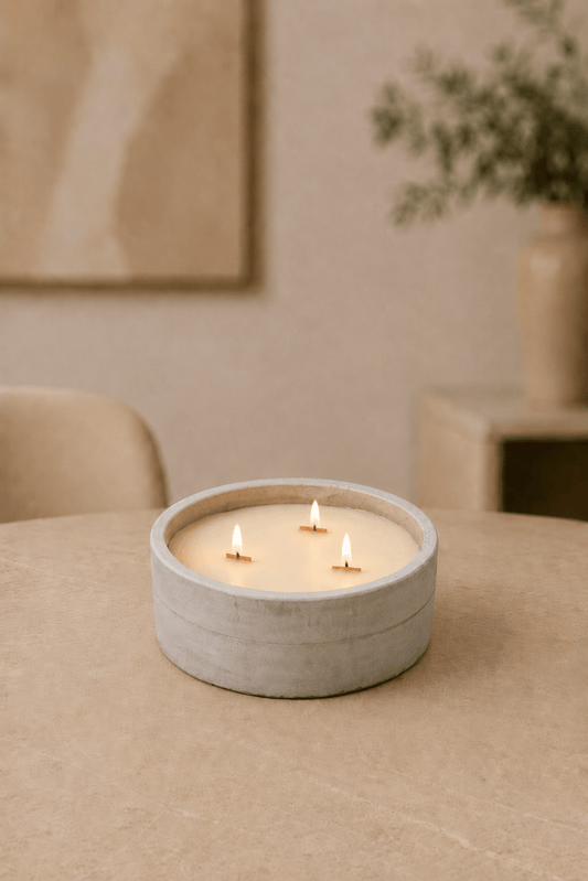 Brandende grote ronde betonnen-houten lontkaars op een lichtbeige tafel in de woonkamer met geblurd dieptezicht