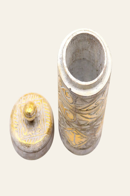 Cilindervormige houten opbergpot met open deksel, verweerd witte afwerking, gouden accenten en uitgesneden geometrische patronen op een lichtbeige achtergrond.