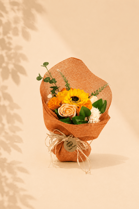 Decoratief staand boeket van oranje zeepbloemen in oranje decoratiepapier met een lint er rond 