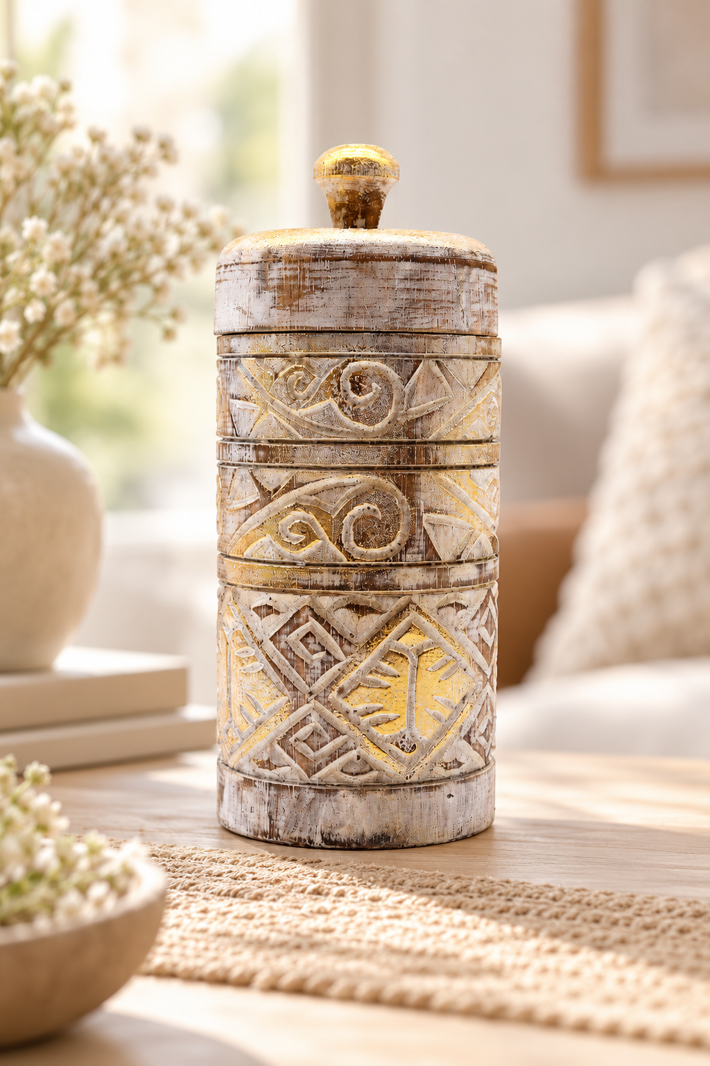 Decoratieve houten opbergpot met deksel in wit en goud op een lichte houten tafel in een rustgevend beige bohemian interieur met geblurde achtergrond.