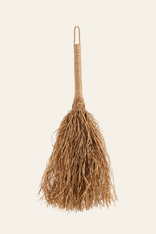 Decoratieve raffia wandbezem naturel op een licht beige achtergrond