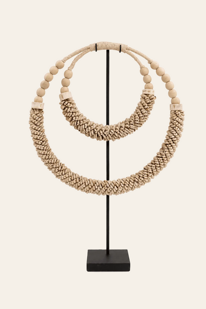 Decoratieve schelpenketting op standaard naturel op een licht beige achtergrond als een productfoto