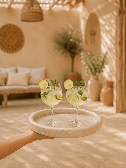 Dienblad van travertijn met opkant gedragen op een hand gevuld met cocktails in geblurde achtergrond 