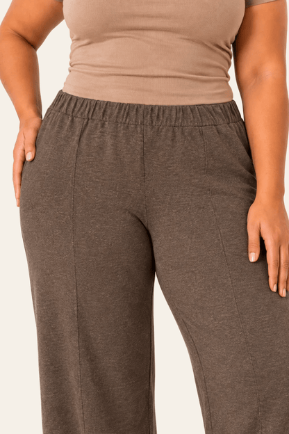 Detail van hoge taille, zijzak en voorstiksels van bruine joggingbroek.