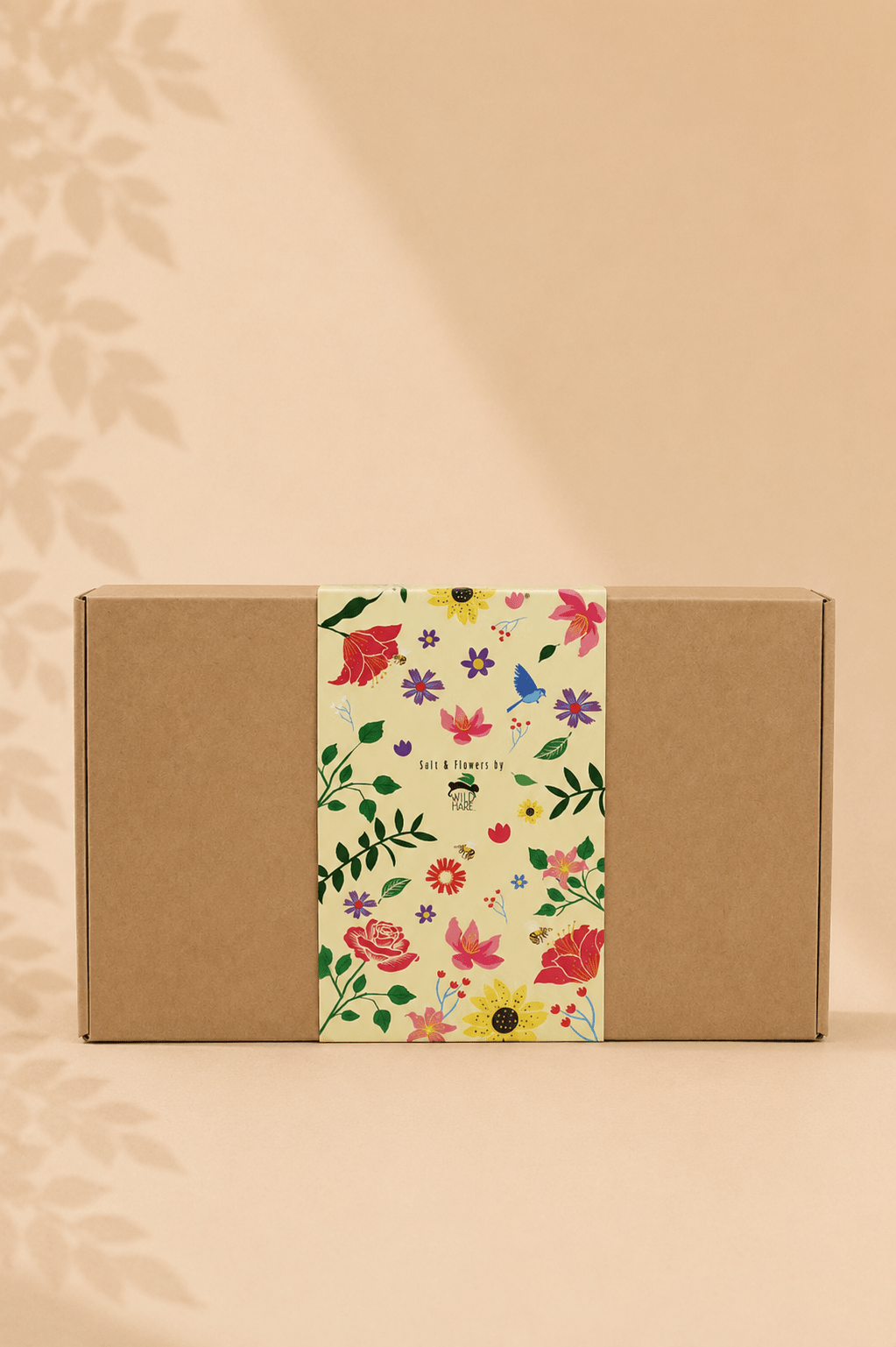 Geschenkdoos met badzout en zeepbloemen in een bruine doos met een gebloemde print rond de doos