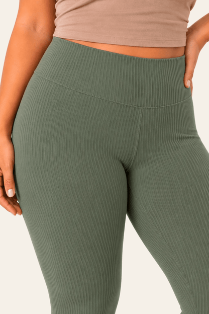 Detail van hoge taille en voorzijde van groene geribde dameslegging.