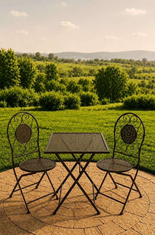 Groene metalen tuinbistroset met vierkante opengewerkte tafel en twee sierstoelen op een terras met uitzicht over een groen landschap
