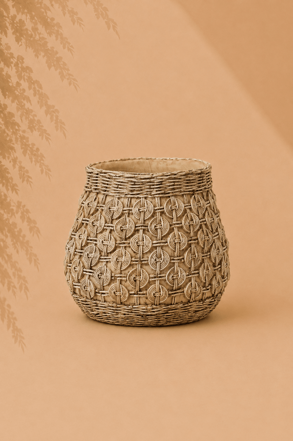 Grote sculpturale plantenbak van beton met knoopreliëf op beige gebladerde achtergrond