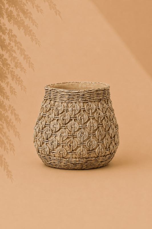 Grote sculpturale plantenbak van beton met knoopreliëf op beige gebladerde achtergrond
