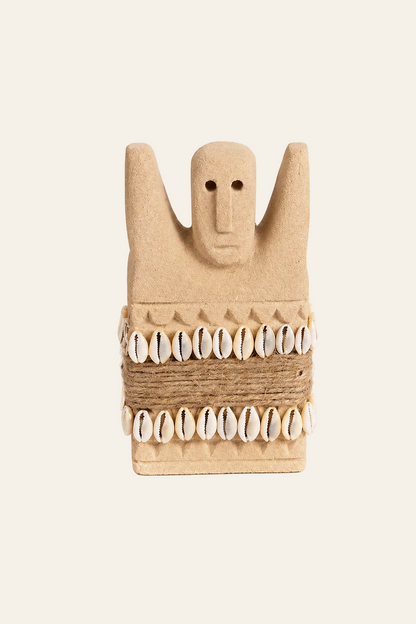 Handgesneden Sumba-beeld van zandsteen met kaurischelpen op licht beige achtergrond
