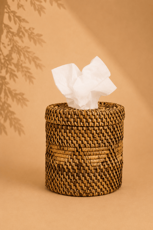 Handgevlochten rotan tissuehouder naturel bruin op een beige gebladerde achtergrond