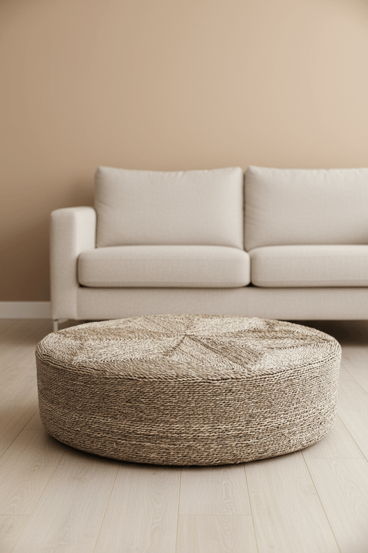 Enorme ronde zeegras poef die voor een sofa staat