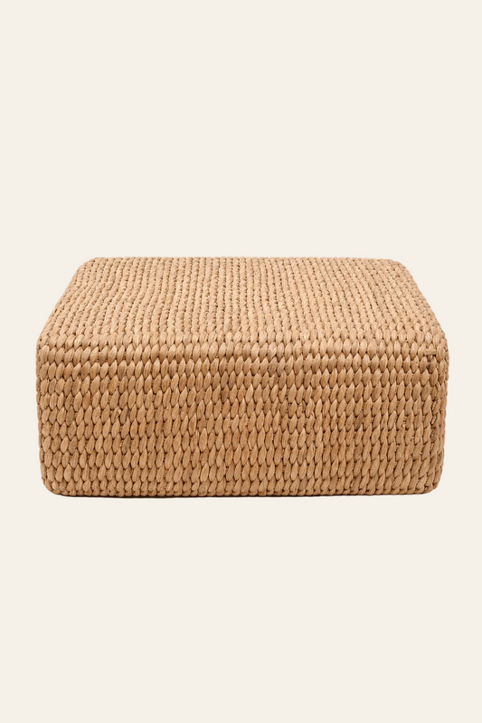 Handgeweven vierkante poef in naturel waterhyacint in een lichtbeige achtergrond productfoto