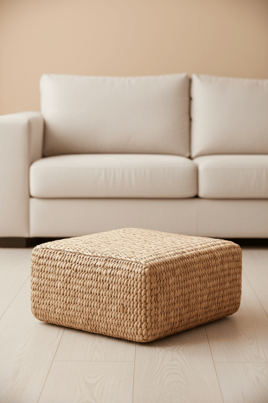 Vierkante poef in naturel waterhyacint in een woonkamer voor de sofa staande