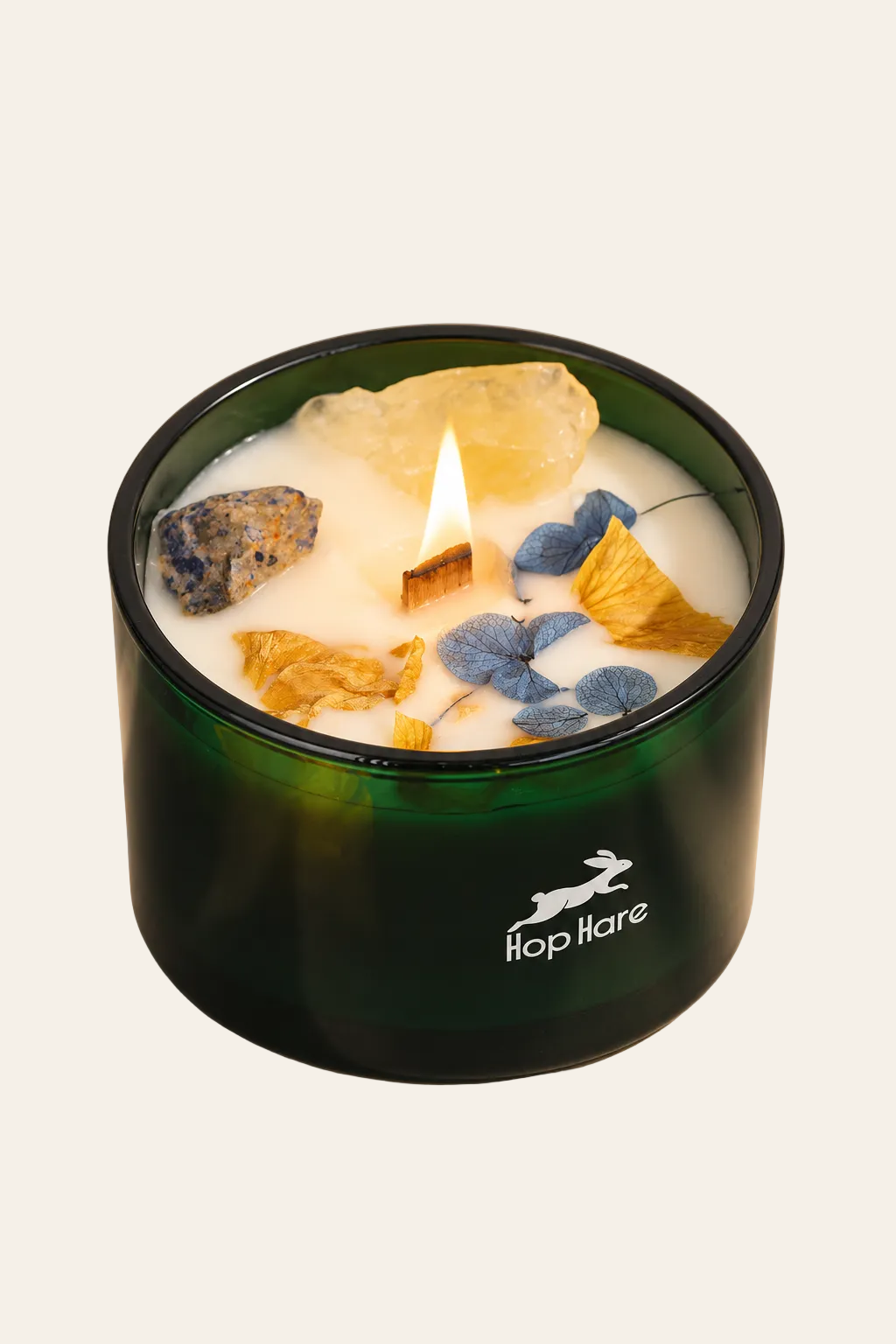 Hop Hare The Sun kristalkaars met brandende houten lont, citrien, sodaliet en gedroogde bloemen in groen glas op beige achtergrond