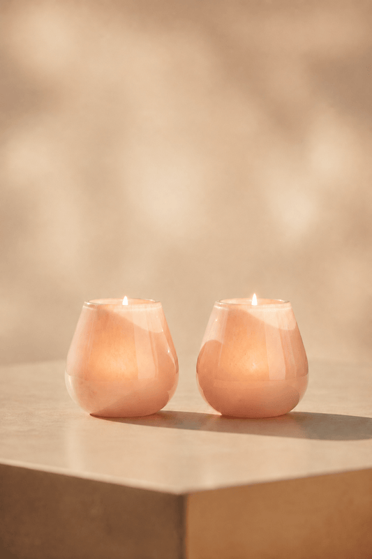 Ivory waxinelichthouder in beige-roze tint oplichtend op lichtbeige tafel  in geblurde achtergrond