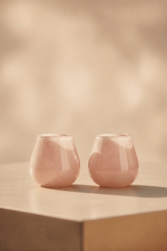 Ivory waxinelichthouder in beige-roze tint. twee kaarsen op lichtbeige tafel met geblurde achtergond