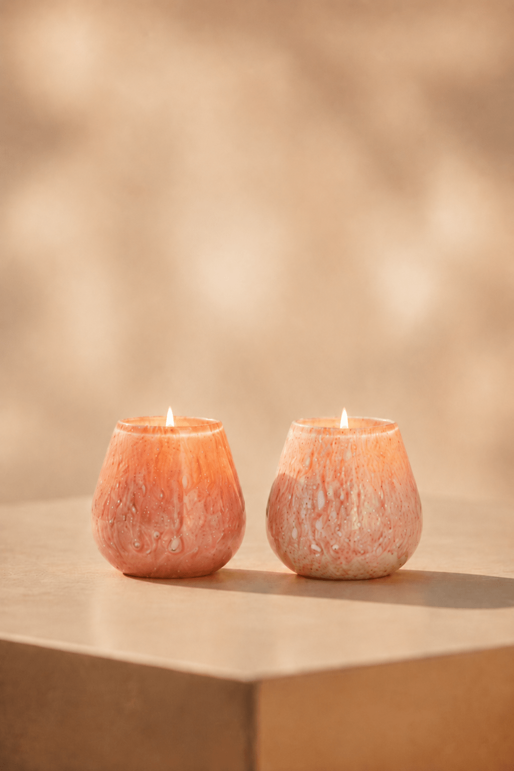 Ivory waxinelichthouder in roze-pink tint, oplichtend op beige tafel in een geblurde achtergrond