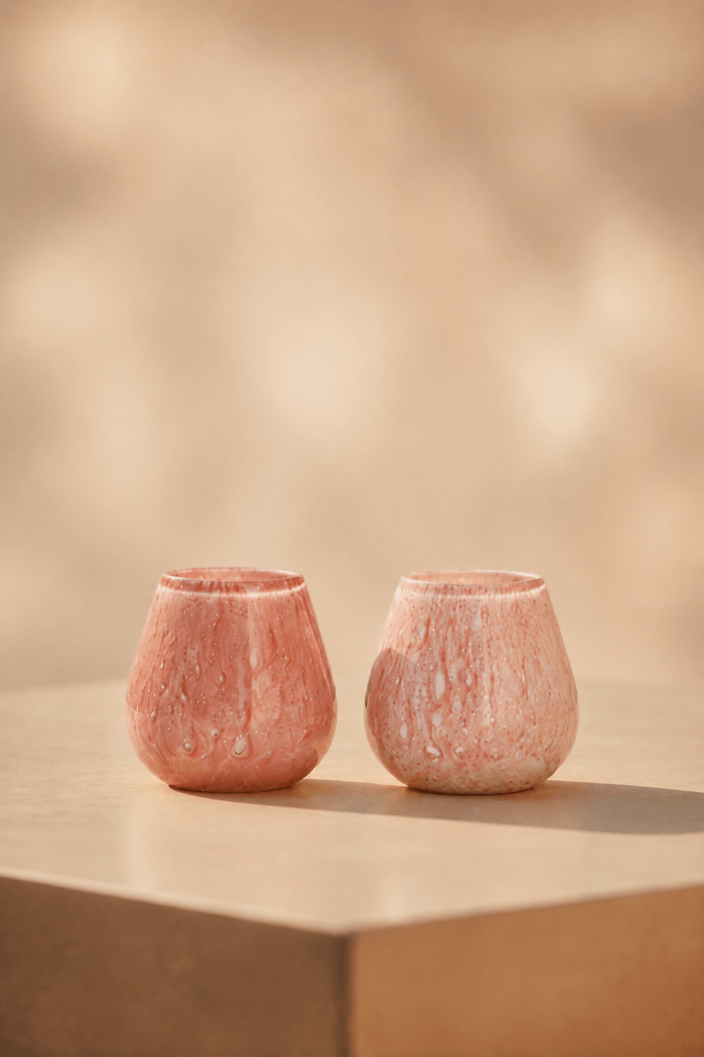 Ivory waxinelichthouder in roze-pink tint op een lichtbeige tafel met geblurde achtergrond