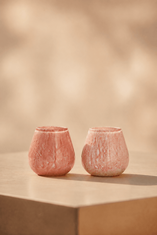 Ivory waxinelichthouder in roze-pink tint op een lichtbeige tafel met geblurde achtergrond