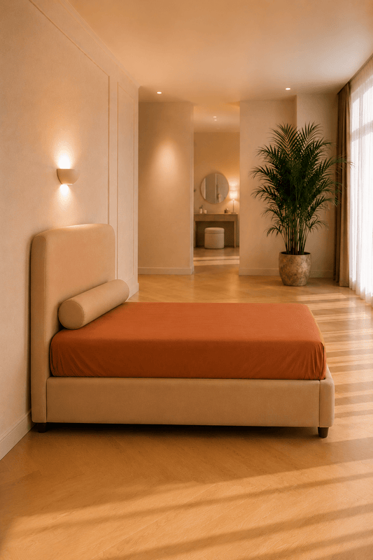Karamelkleurig hoeslaken van biologisch percal katoen strak aangebracht rond een matras in een warme slaapkamer