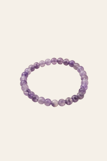 Manifestatie armband met amethist voor innerlijke rust op een licht beige achtergrond als productfoto
