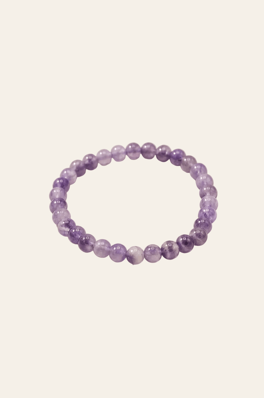 Manifestatie armband met amethist voor innerlijke rust op een licht beige achtergrond als productfoto