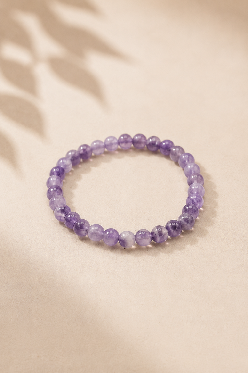Manifestatie armband met amethist voor innerlijke rust op een licht gebladerde beige achtergrond