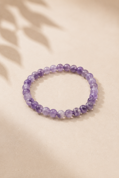 Manifestatie armband met amethist voor innerlijke rust op een licht gebladerde beige achtergrond