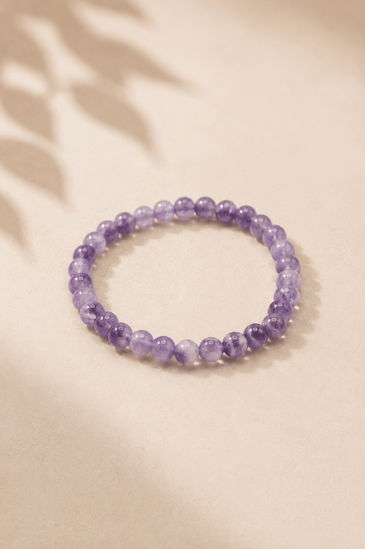 Manifestatie armband met amethist voor innerlijke rust op een licht gebladerde beige achtergrond