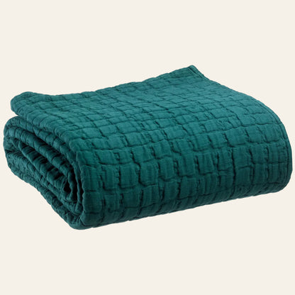 Opgevouwen Swami bedsprei van 100% katoen in petroleumblauwkleur met zichtbare stonewashed reliëfstructuur
