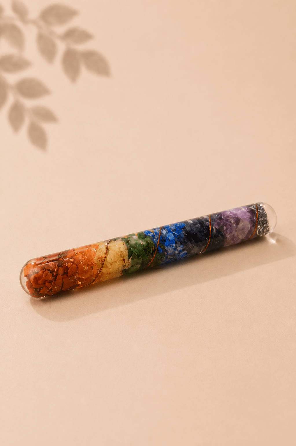 Orgoniet healing wand met chakra-edelstenen en koper op een gebladerde beige achtergrond