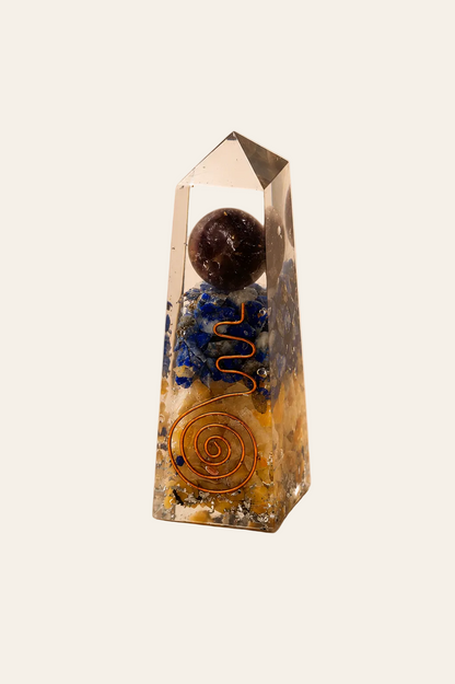 Orgoniet obelisk met lapis lazuli en gele aventurijn op een licht beige achtergrond als productfoto